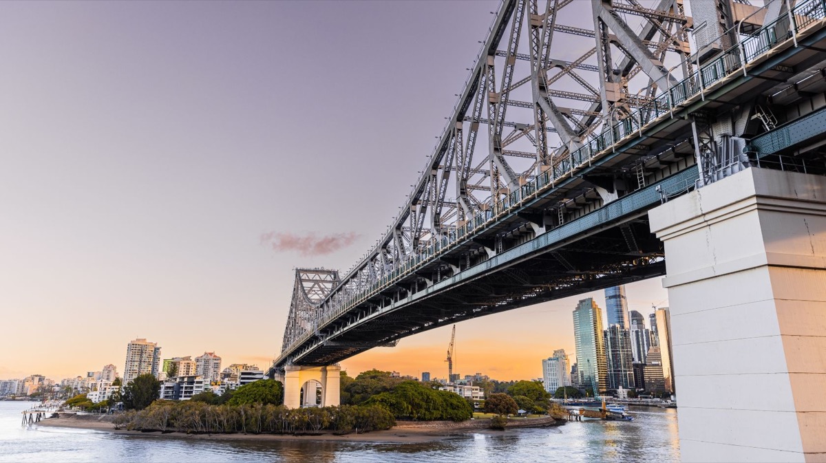 The Story Bridge over the Brisbane River at golden hour, city towers behind